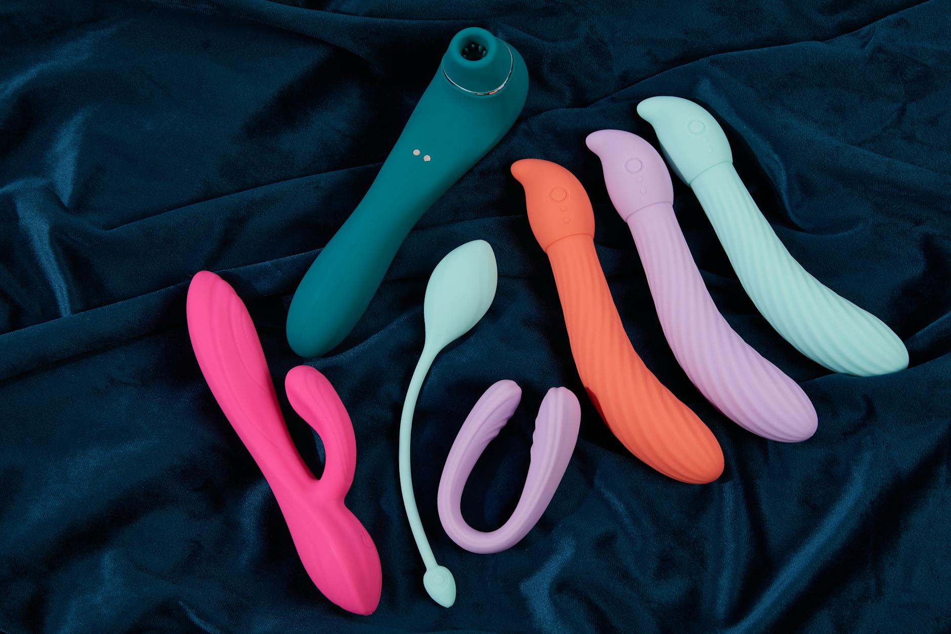 Vibrant display of colorful silicone vibrators arranged on dark blue fabric