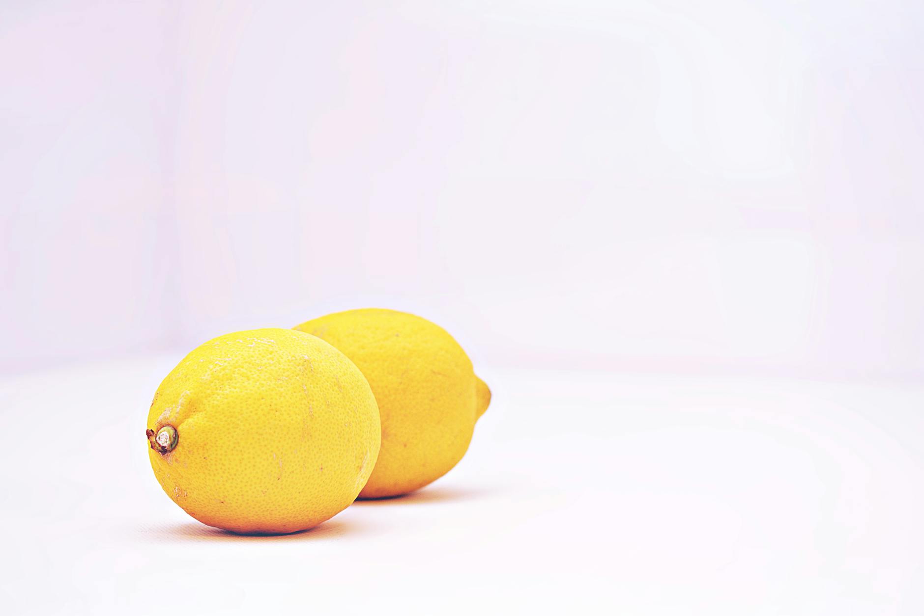 Two vibrant lemons on a minimalistic white background, symbolizing freshness and renewal