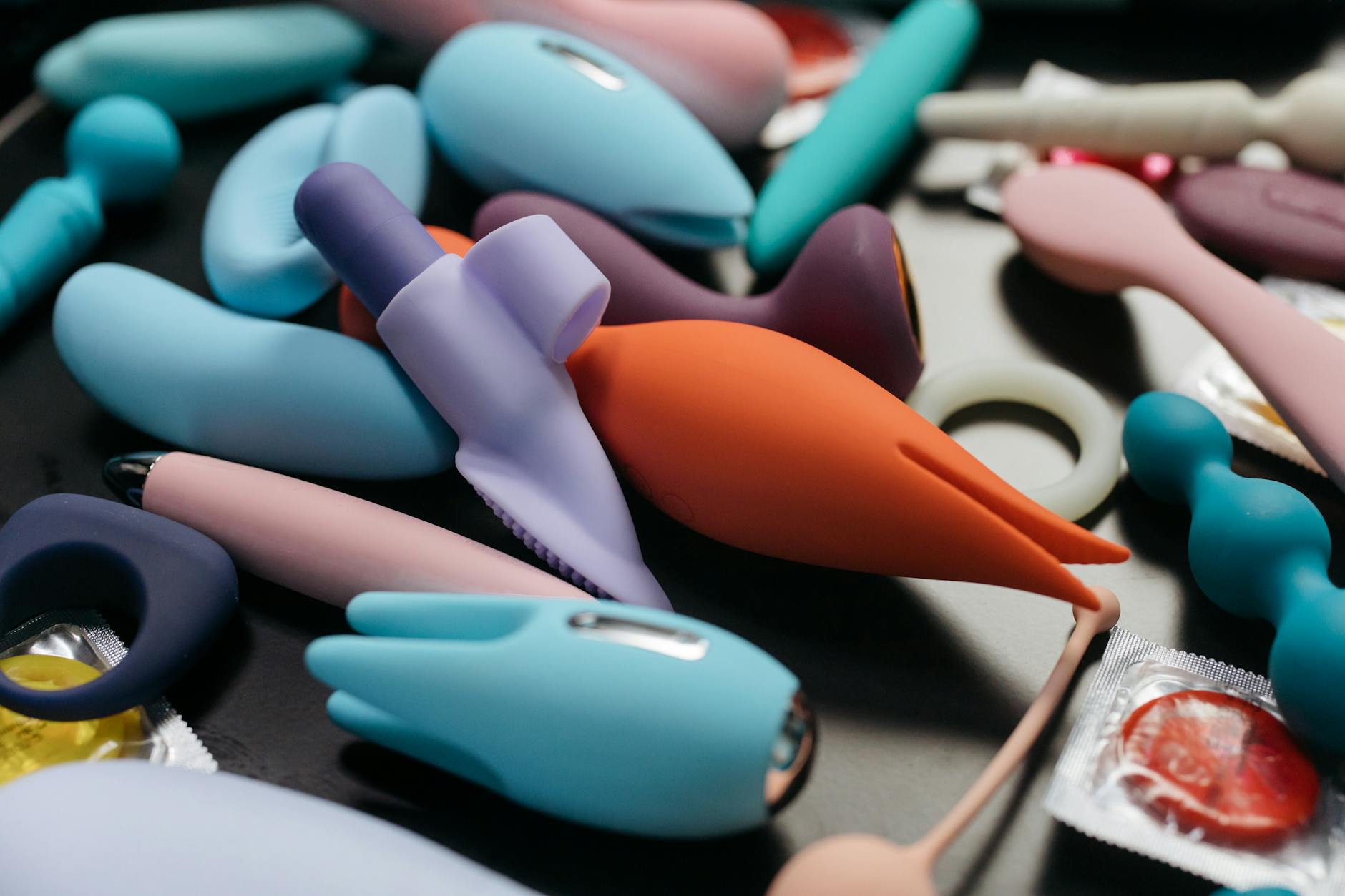 Close-up of a hand holding a modern clitoral vibrator against a minimalist purple backdrop