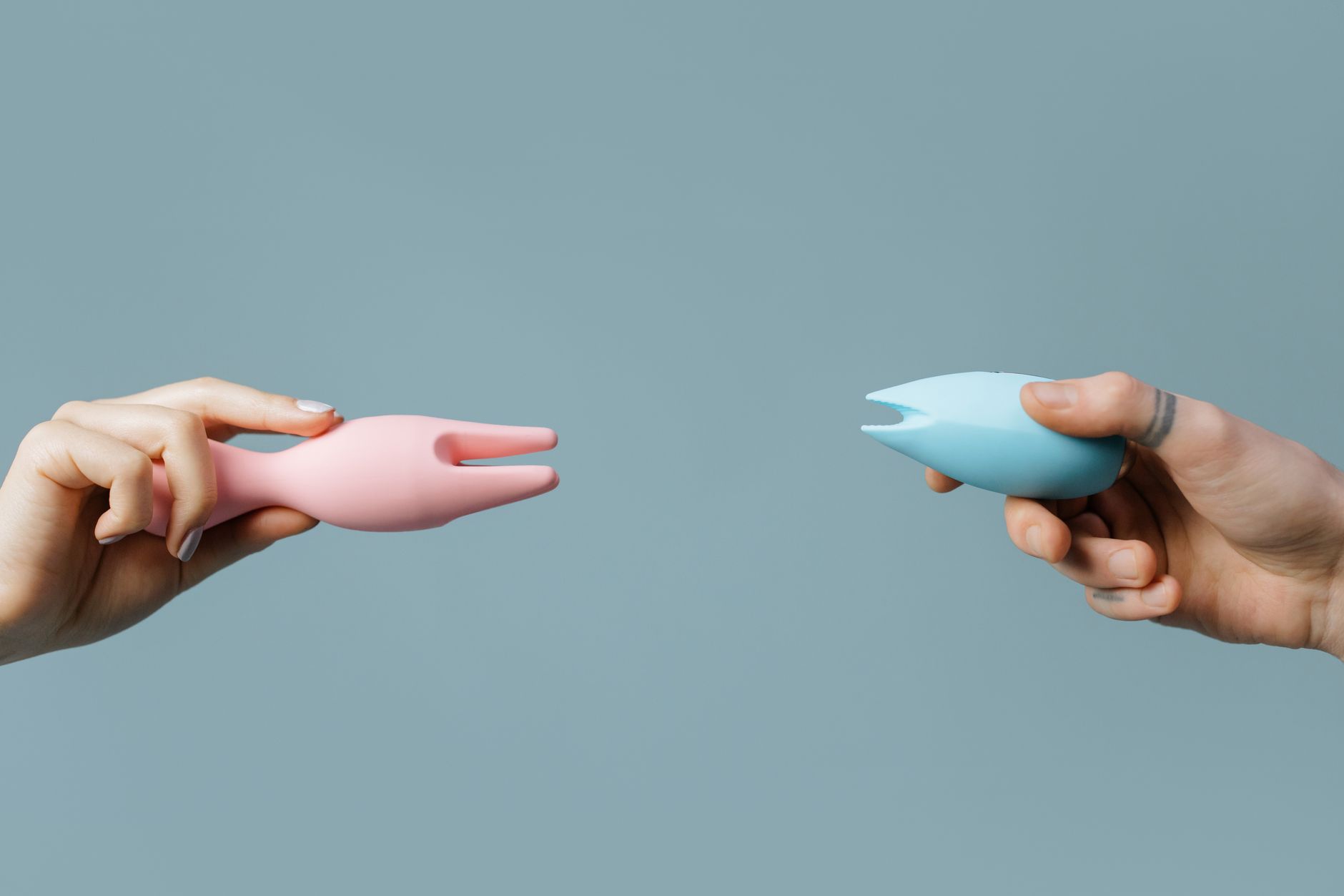 Hands holding a sleek blue vibrator against a purple background, representing intimate pleasure without performance expectations.