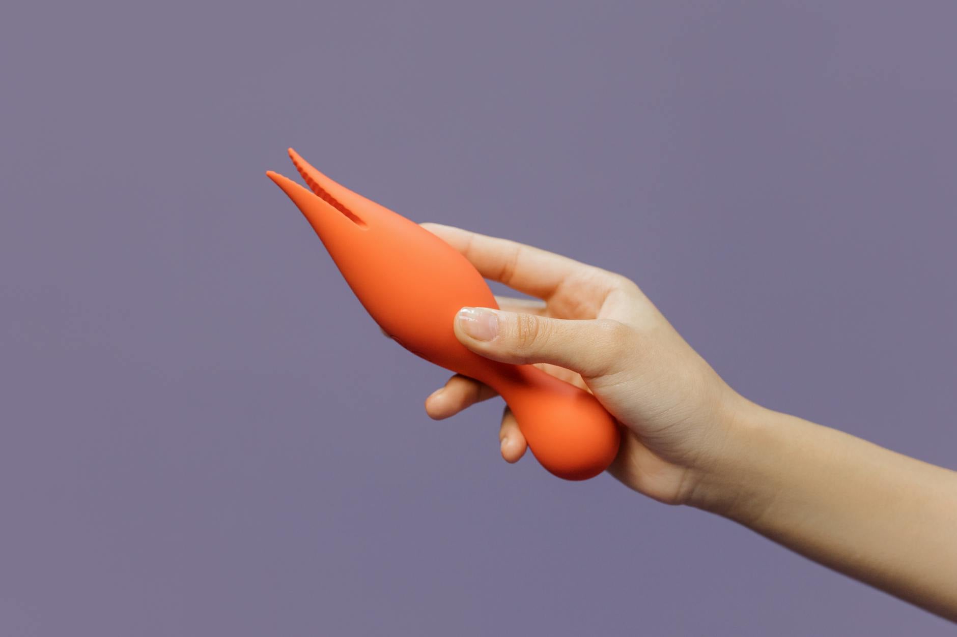 Hand holding a lemon vibrator against a purple backdrop, modern and minimalist