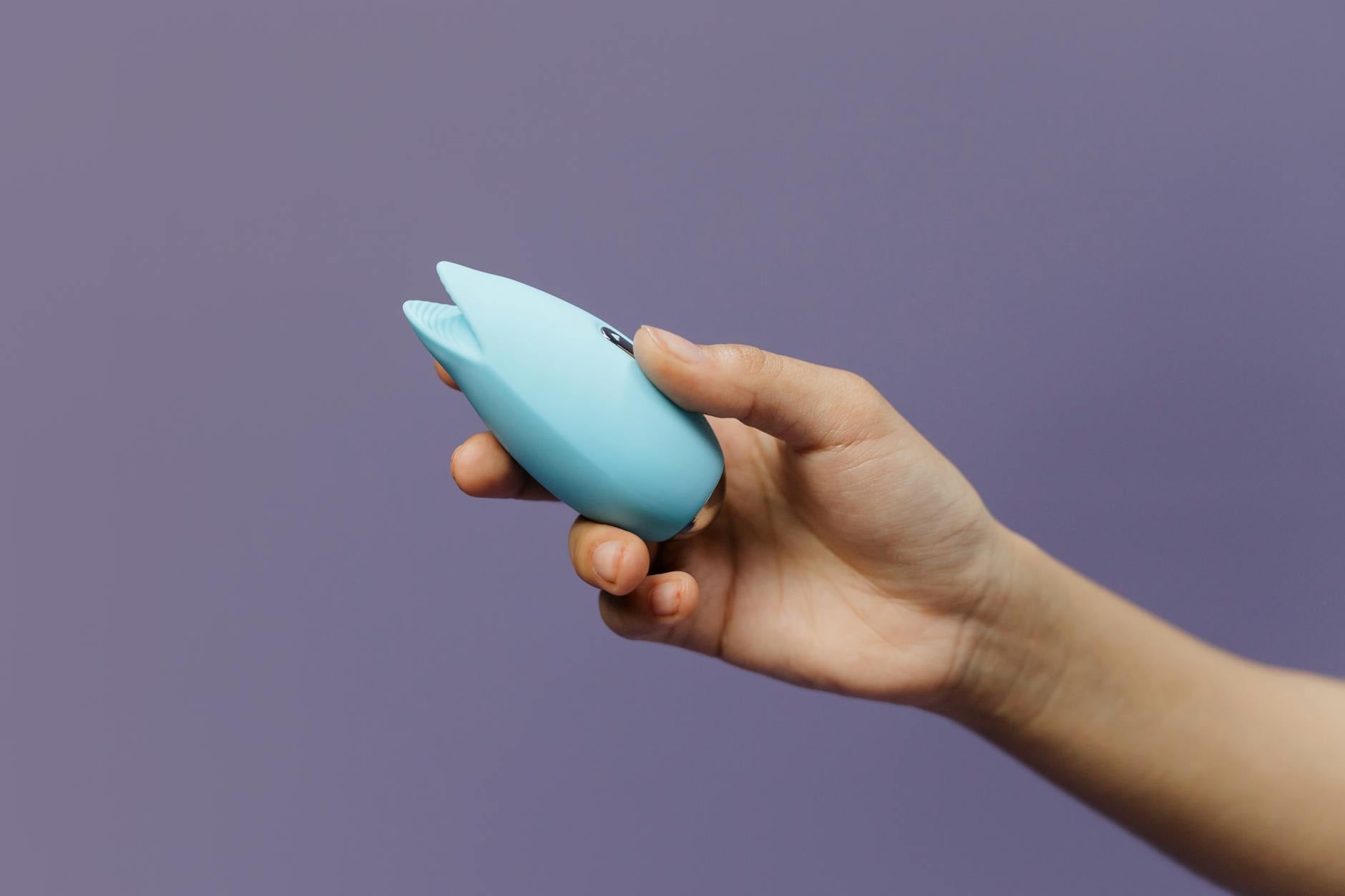 A lemon clitoral vibrator held in hand against a purple background, representing modern solutions to intimate challenges