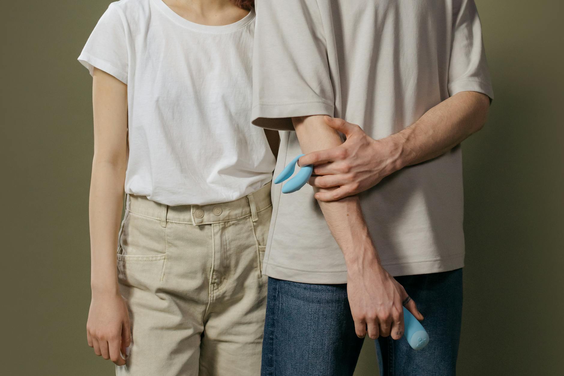 A couple holding a blue vibrator together indoors, symbolizing intimate connection and modern pleasure without pressure
